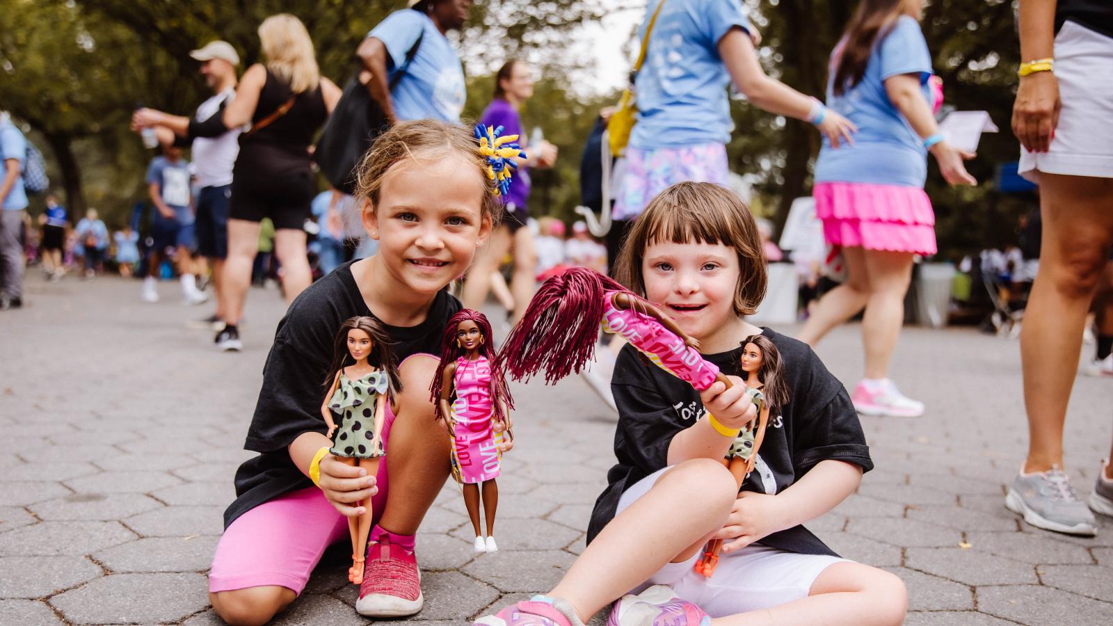 two young girls sitting playing with Barbie dolls