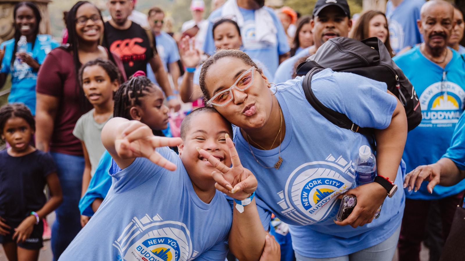 Two women smiling doing a peace sign at the camera